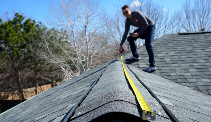 man on roof with measuring tape